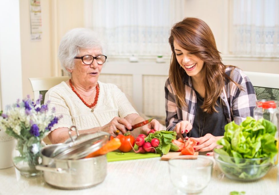 Grandmother and granddaughter preparing food at home.